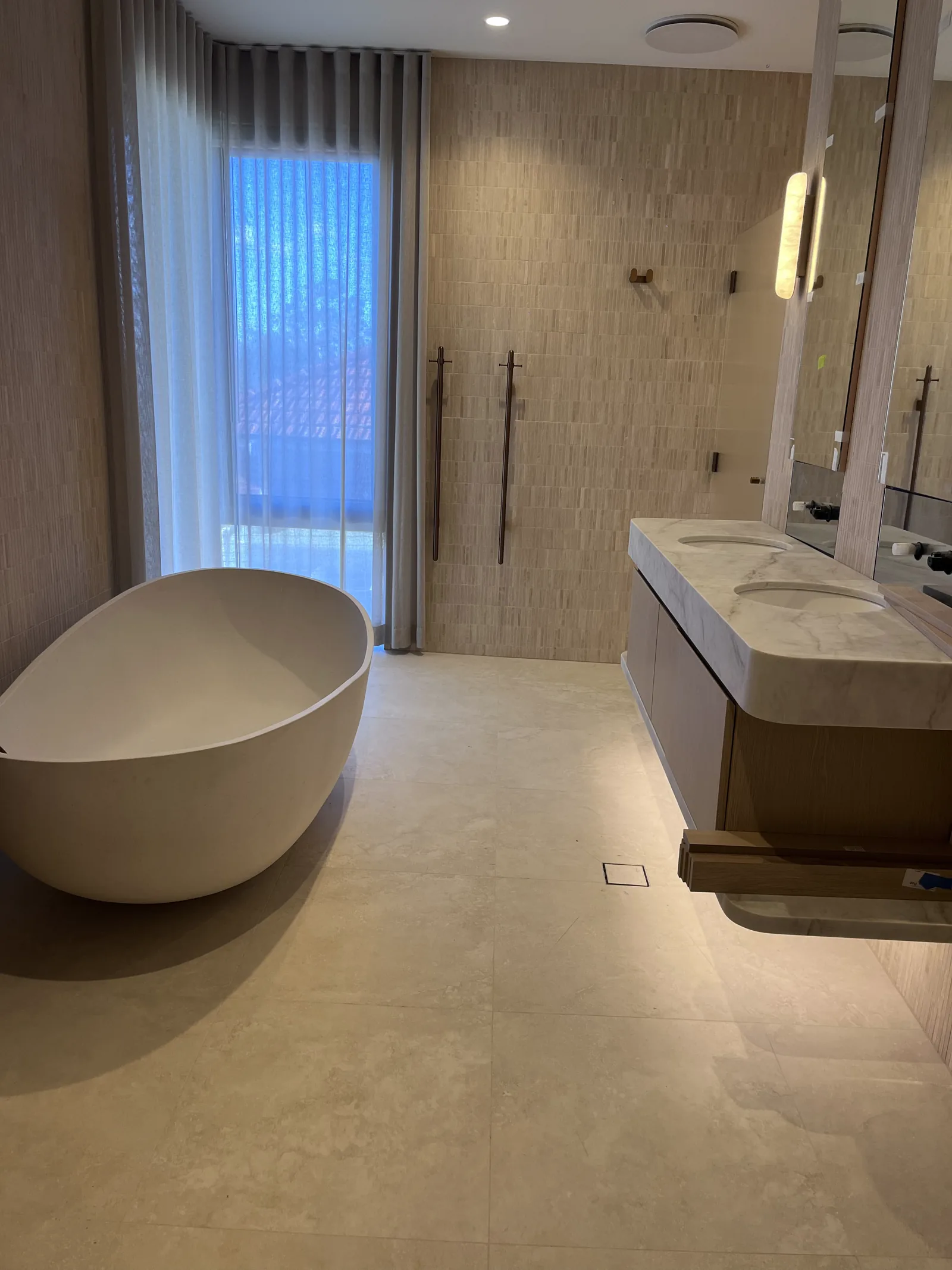 Warm-toned bathroom with a freestanding bath, full-height textured tiles and a stone vanity.