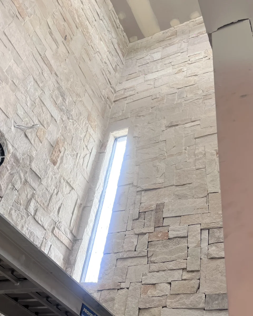 Tall interior feature wall finished with stacked stone cladding.