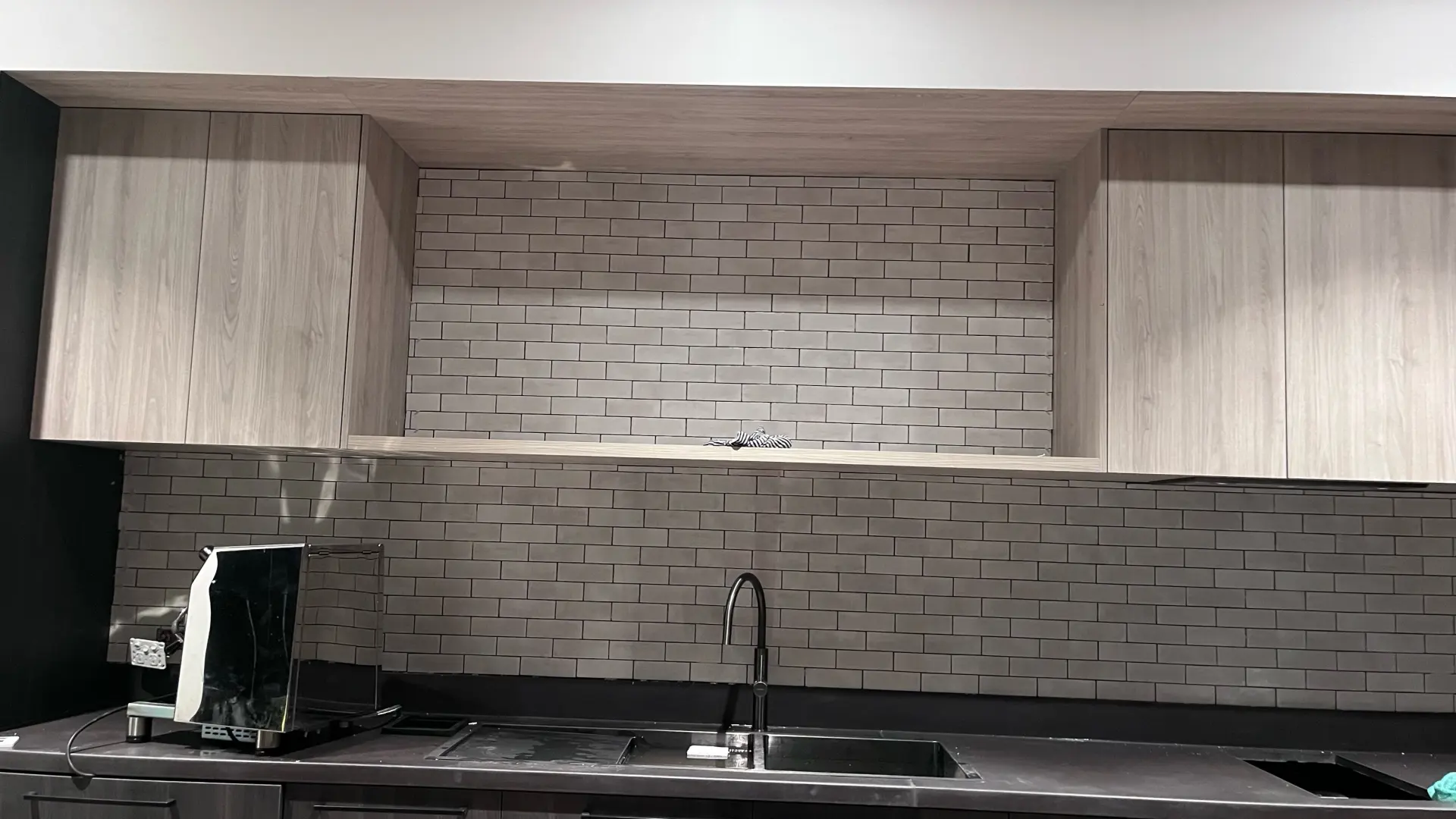 Finished grey kitchen splashback tiles framed by timber cabinetry in a Canberra home.