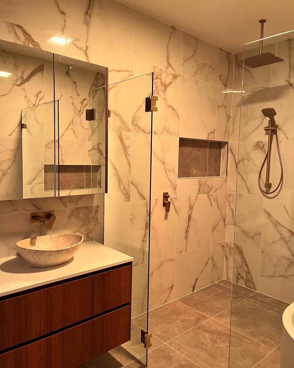 Finished marble-look bathroom tiling with shower screen and niche.